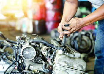 Close up hand of attractive man working hard and fix Auto mechanic on car engine in mechanics garage. Repair service