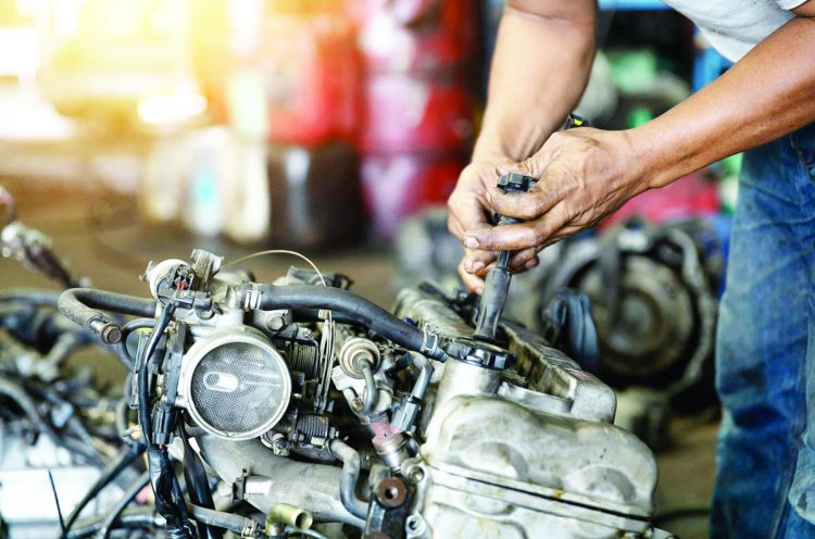 Close up hand of attractive man working hard and fix Auto mechanic on car engine in mechanics garage. Repair service